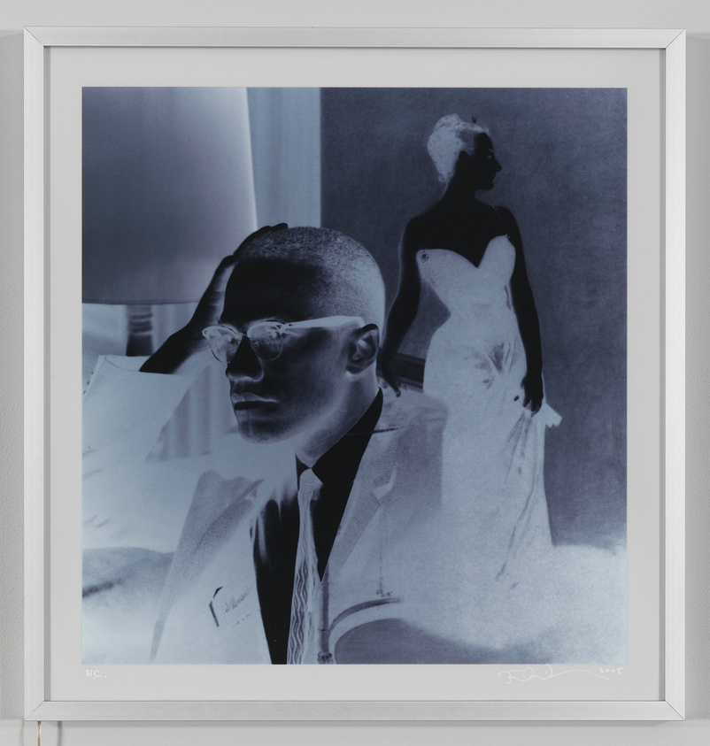 A framed monochromatic artwork featuring a double exposure portrait. The primary subject is a person in the foreground with a serious expression, wearing glasses and a suit, holding their head with one hand. In the background, a silhouette of a person in a dress is visible, creating a ghostly overlay effect. The image has a blue tint and is signed by the artist in the lower right corner.