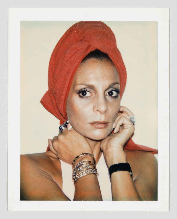Person with a red towel wrapped around their head, wearing jewelry and looking directly at the camera.