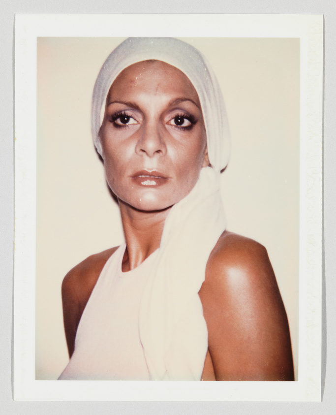 Person with serious expression wearing a white headscarf and sleeveless top, facing forward against a plain background.