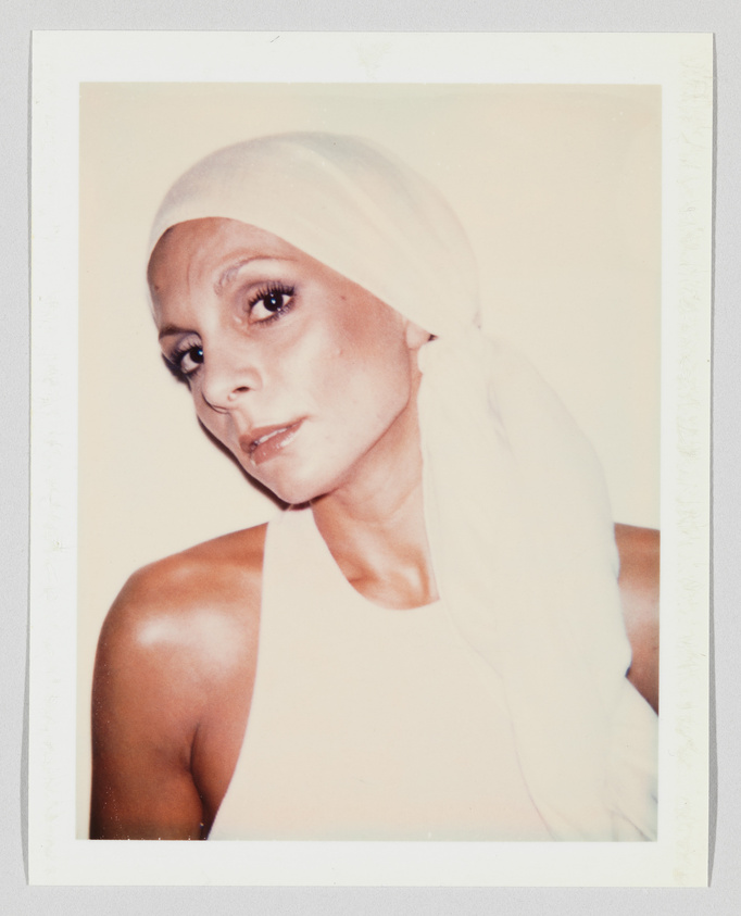 Person wearing a white headscarf and sleeveless top, looking slightly to the side with a neutral expression.