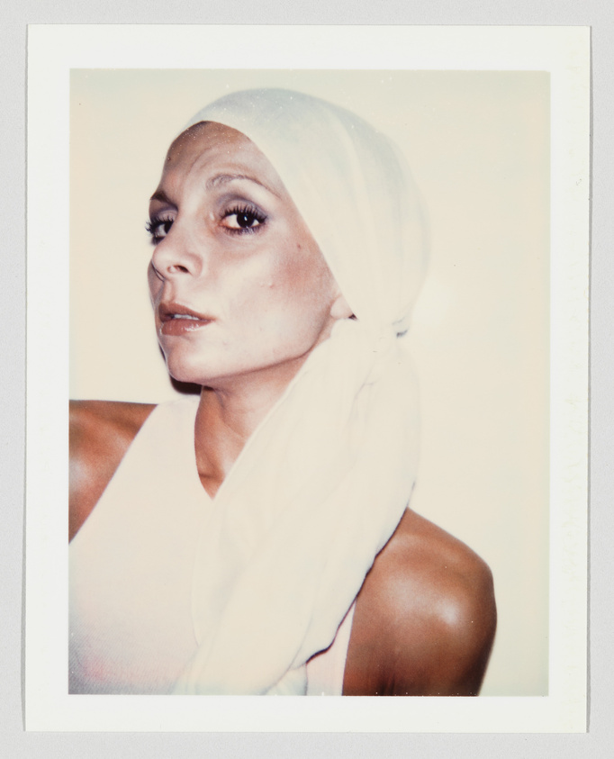 Person wearing a white headscarf and sleeveless top, looking slightly to the side with a neutral expression.