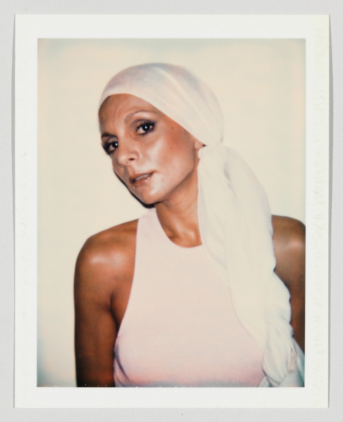 Woman wearing a sleeveless light pink top and a white headscarf, looking slightly to the side.