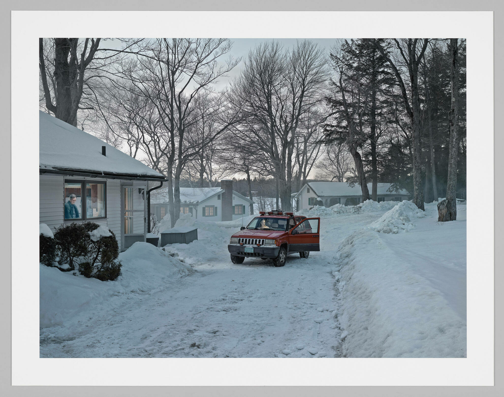 A red car parked in the middle of a neighborhood road covered with the passenger door open. 