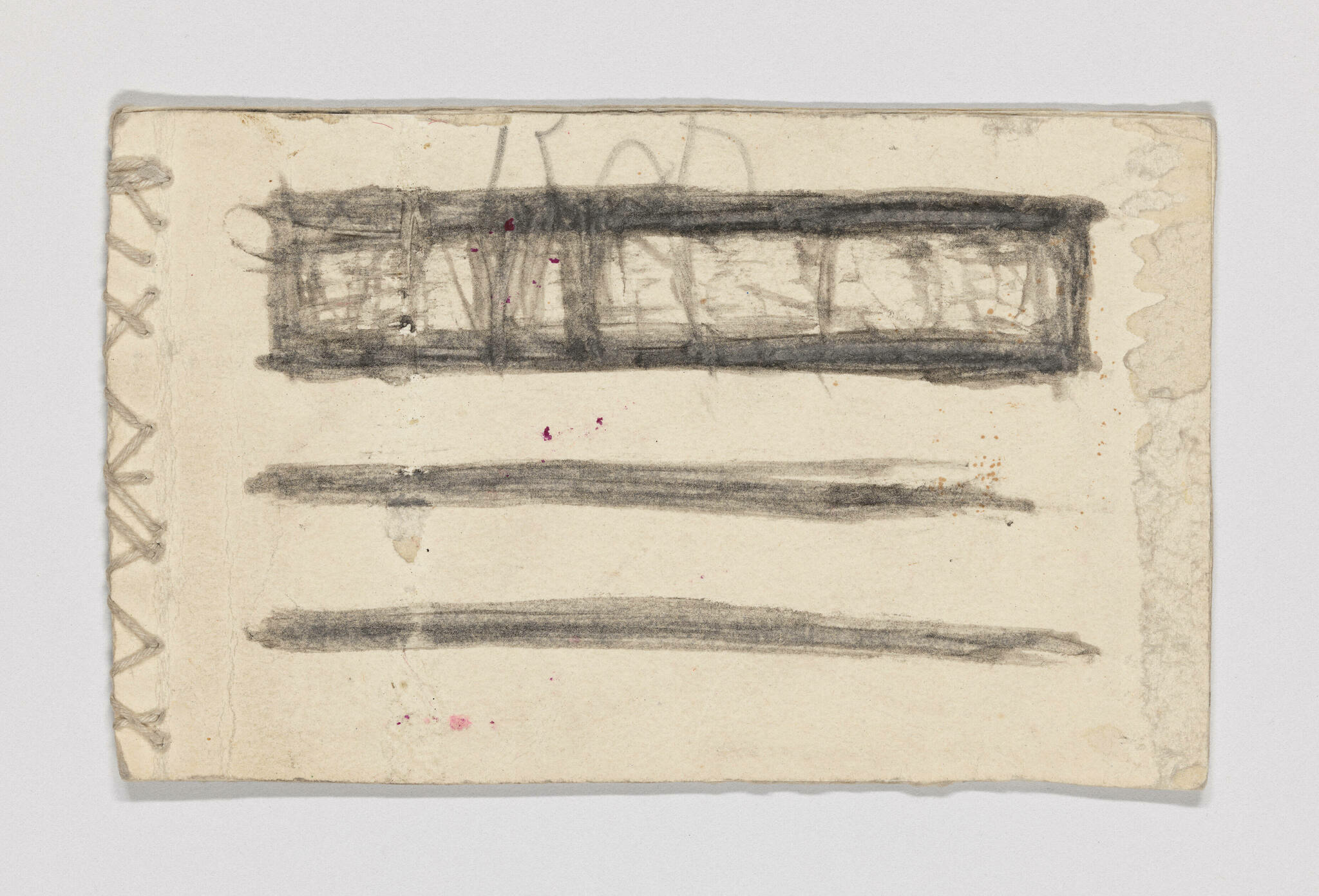 A worn piece of paper with rough edges and stitching on the left side, featuring abstract charcoal or pencil strokes. There are three horizontal lines with a rectangular shape above, all in a smudged black medium, and small specks of red pigment scattered across the surface.