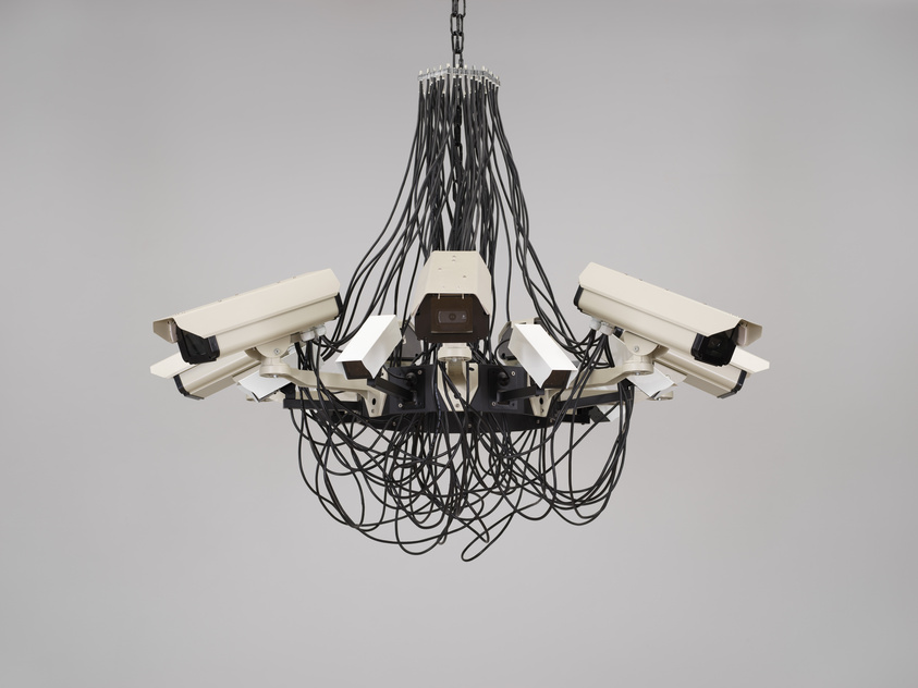 A chandelier made from several security cameras and many black cables hanging from the ceiling.