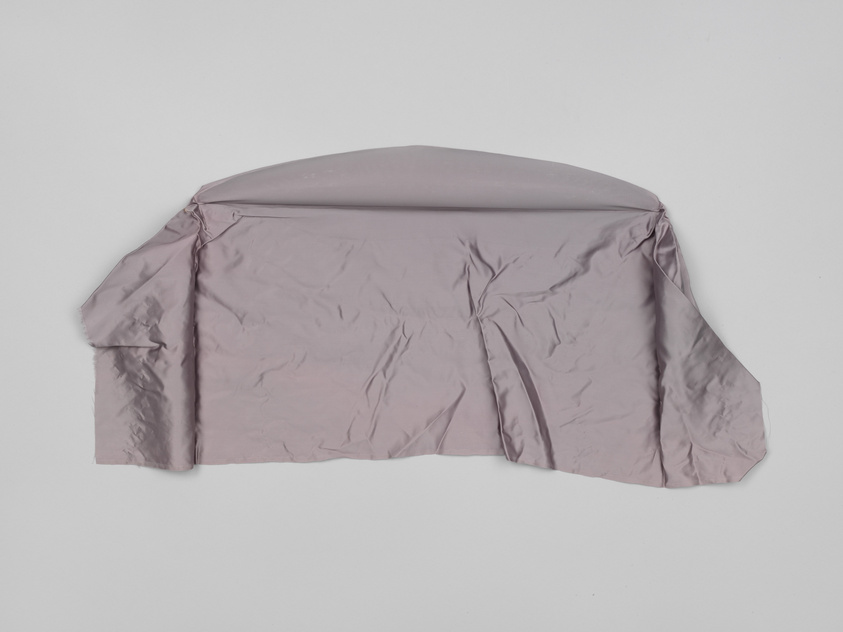 A wrinkled mauve shirt with short sleeves laid out flat on a white background.