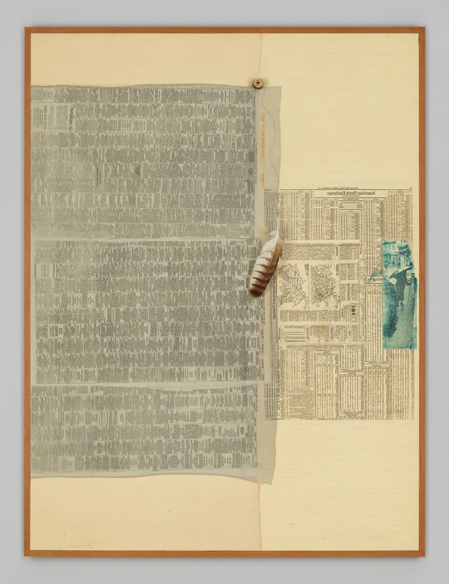 A mixed media artwork featuring a large piece of newspaper with text, partially covering a beige background, pinned at the top left corner. A smaller newspaper clipping with visible text and a blue-green painted section is attached to the right side. A striped feather hangs from a string pinned under the larger newspaper piece. The entire composition is framed in a light wooden frame.