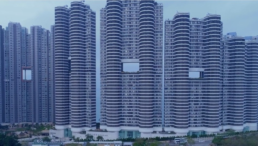 Modern high-rise apartment buildings with unique curved architecture against a cloudy sky.