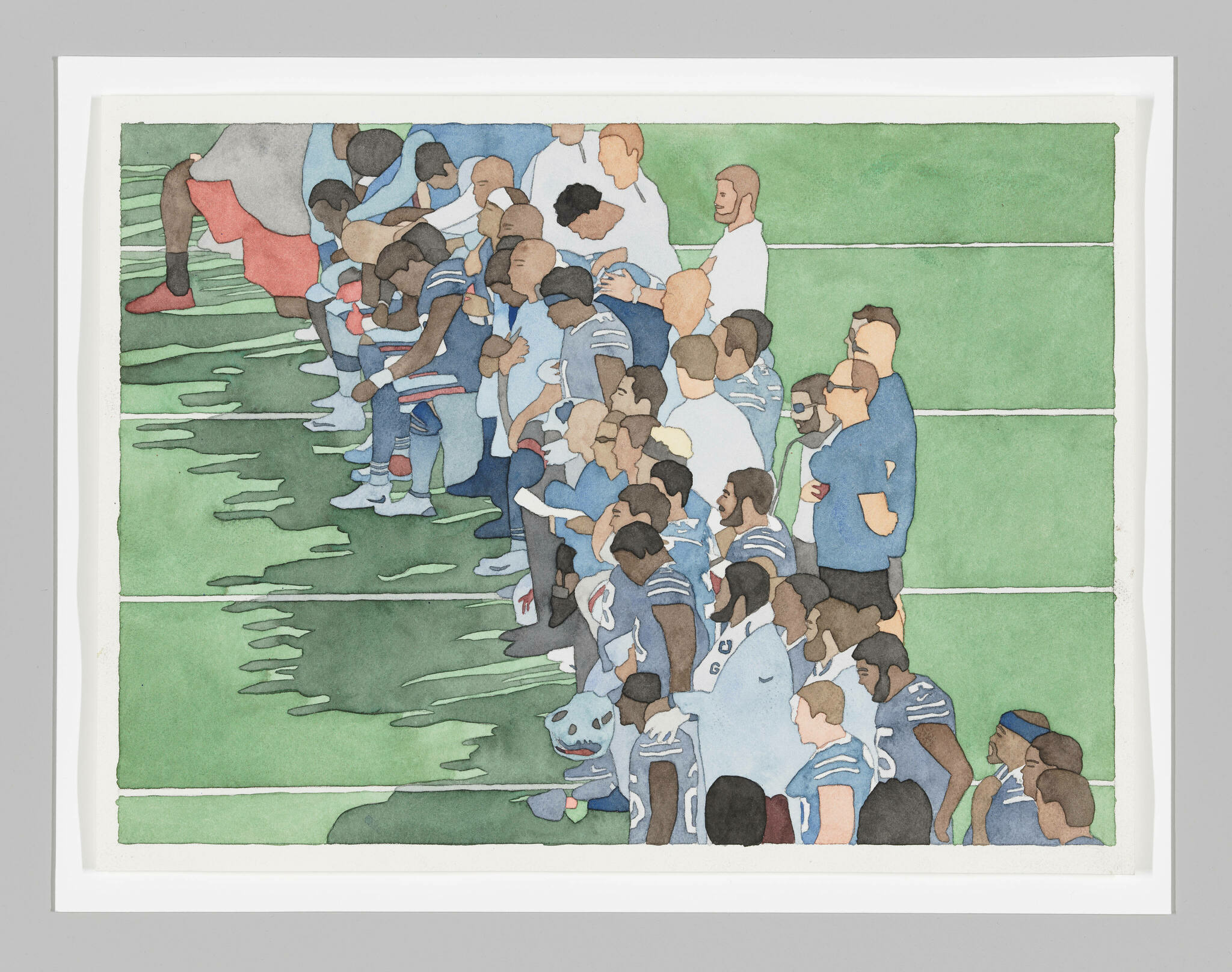 An aerial view of Black football players taking a knee and/or bowing their heads, accompanied by coaching staff.