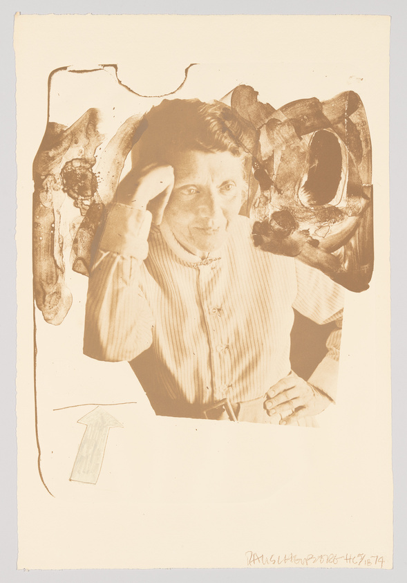 A vintage sepia-toned photograph of a person peering through a roughly torn hole in a surface, with their head and one arm visible. The individual is making a saluting gesture with their hand to their forehead and looking directly at the camera with an intense gaze. The bottom right corner of the image contains handwritten text and a date. There is also a small arrow drawing pointing upwards on the lower left side of the image.
