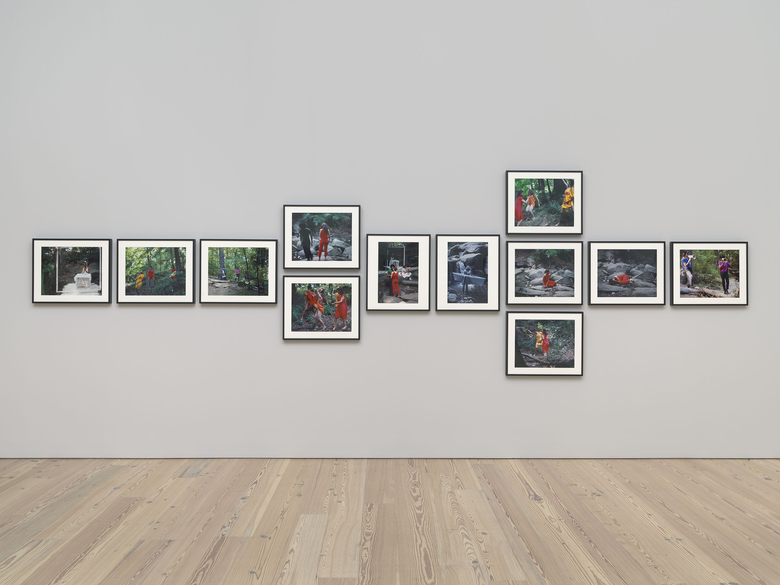 A series of framed photographs displayed on a gallery wall, featuring outdoor scenes with people in various activities.