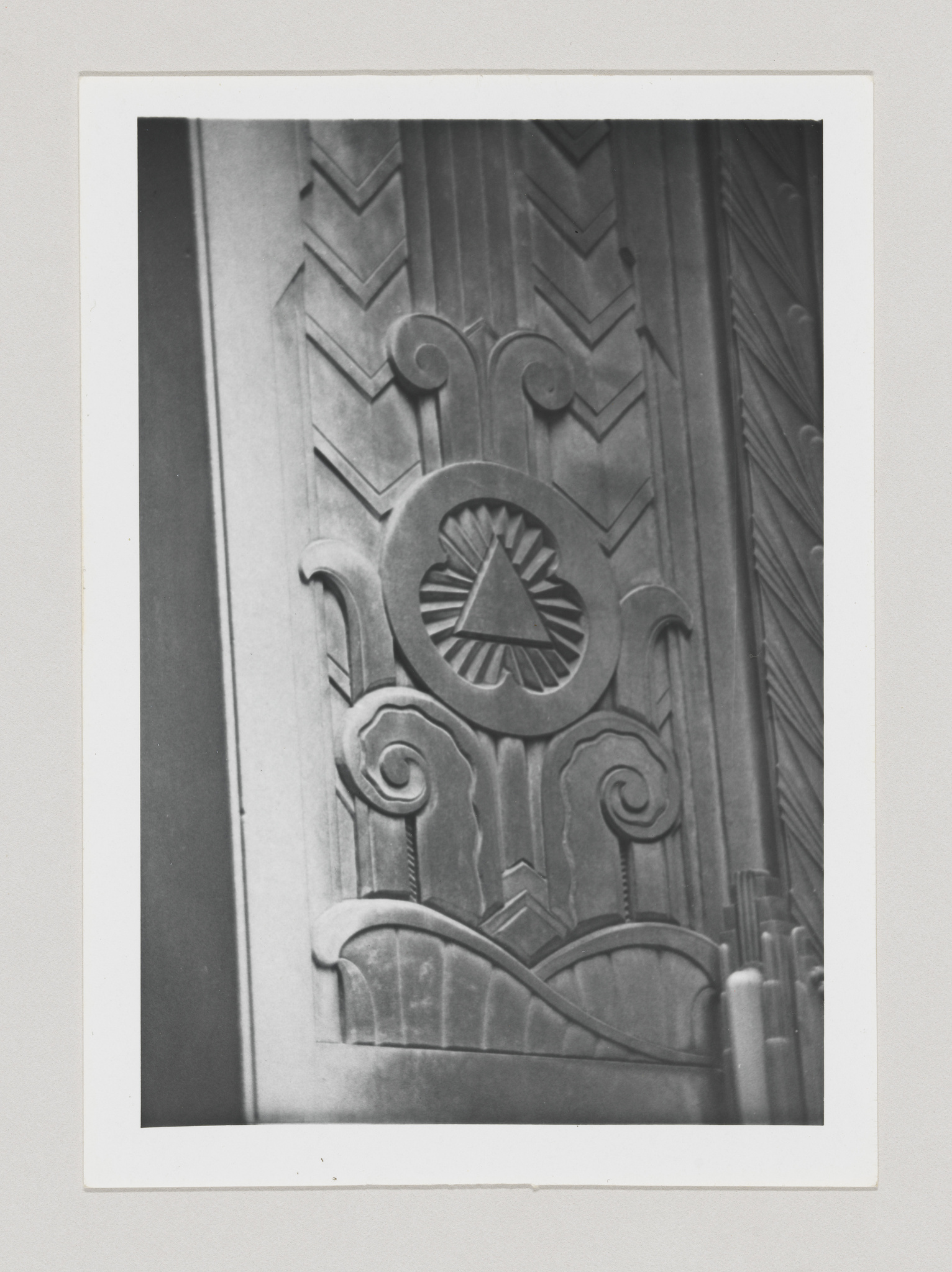 A black and white photo of an art deco architectural detail featuring geometric patterns and a stylized sunburst design.