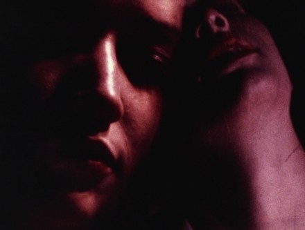 Two faces in low light, close together, creating a dramatic and shadowy effect.