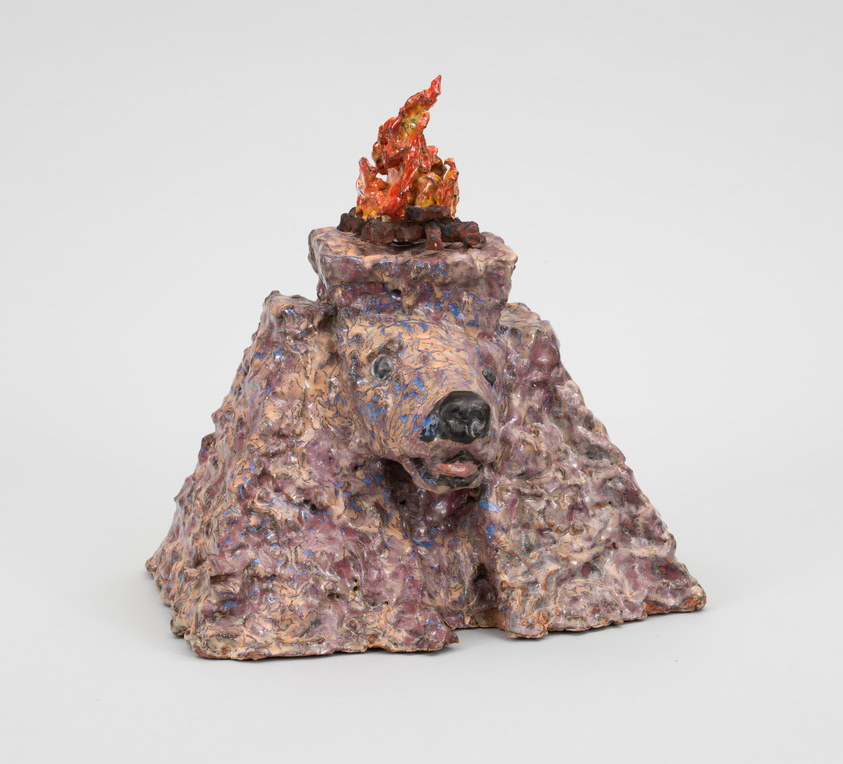 A ceramic sculpture of a bear with a campfire on its head, featuring a textured, multicolored surface and a realistic flame.
