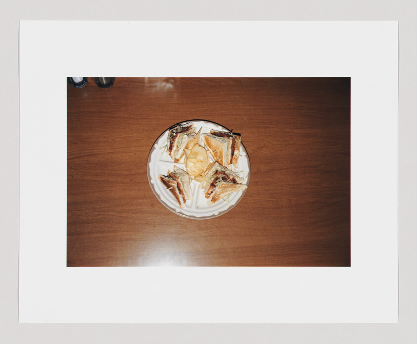 A plate with four club sandwich quarters and a small pile of potato chips in the center.