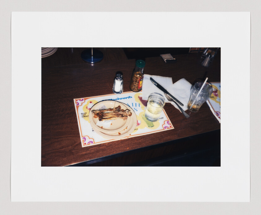 A finished meal with empty bones on a plate, a glass of water, and utensils on a placemat.