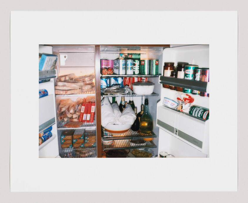 A refrigerator filled with bread, canned drinks, bottles, jars, packaged food, and bowls on the shelves.