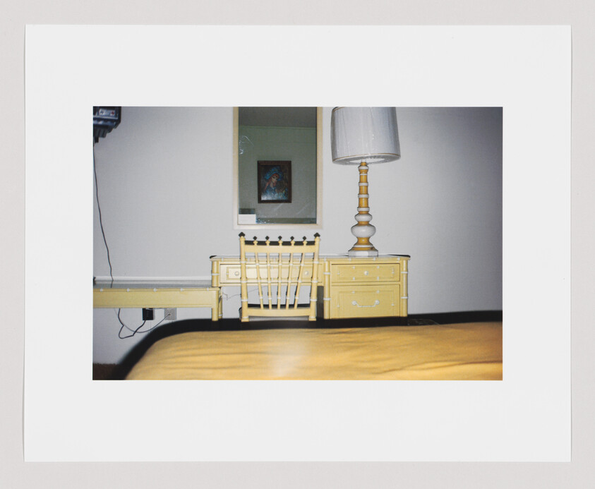 Yellow desk with matching chair and lamp against a wall, with a framed picture and mirror above.