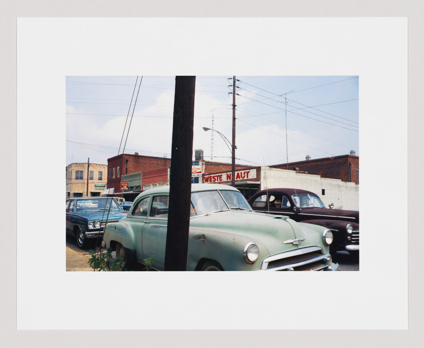 Several old cars are parked on a street near a building with a sign that reads "WESTERN AUT."