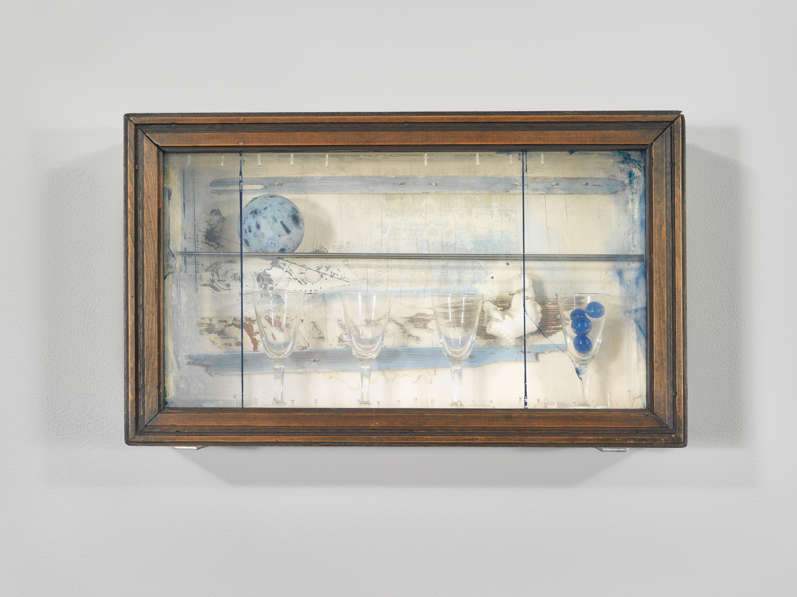 A framed three-dimensional artwork with glassware and a speckled egg, exhibiting a blend of natural and vintage aesthetics.