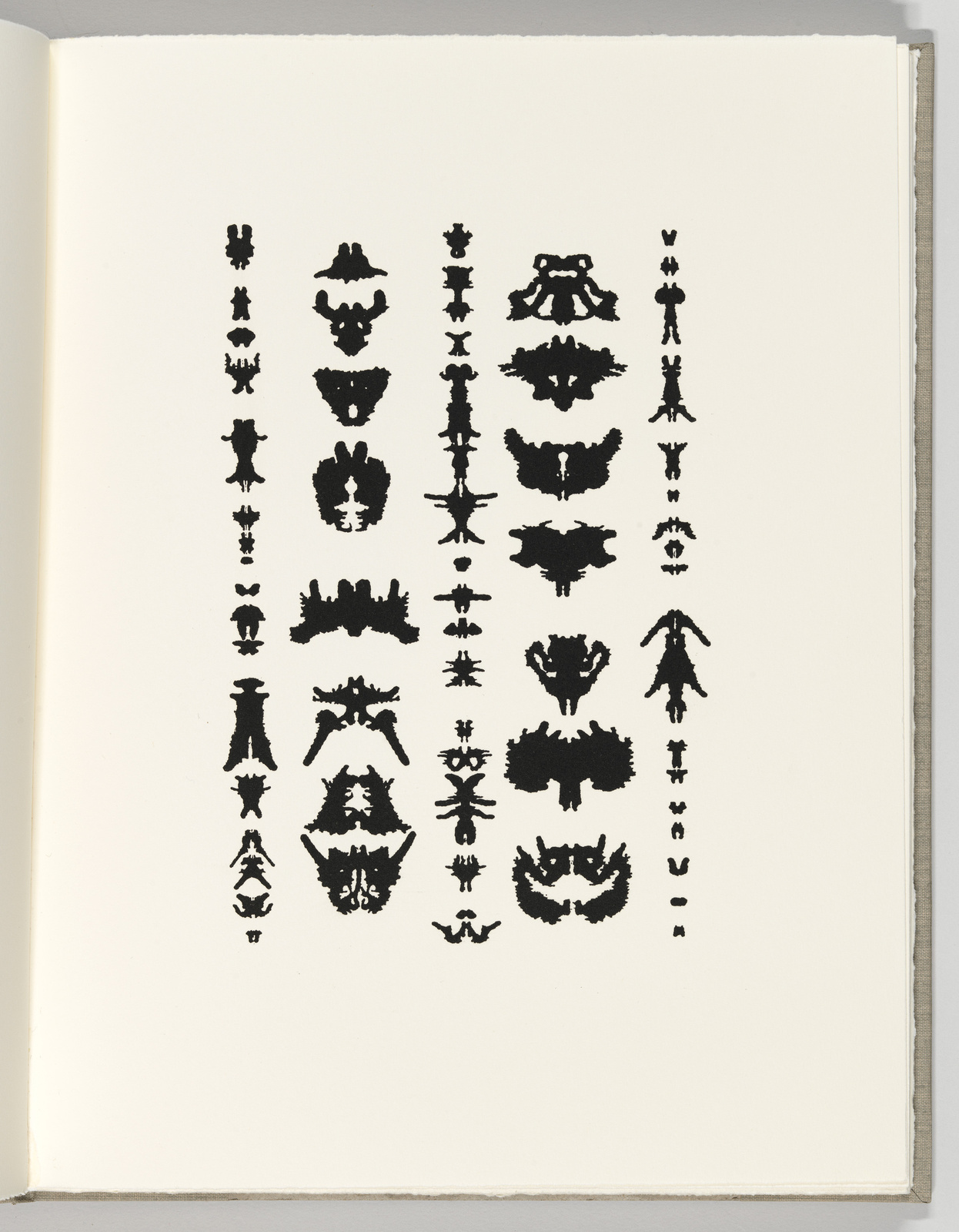 A page from a book displaying a collection of black inkblot symmetrical patterns, reminiscent of a Rorschach test, arranged in three vertical columns.