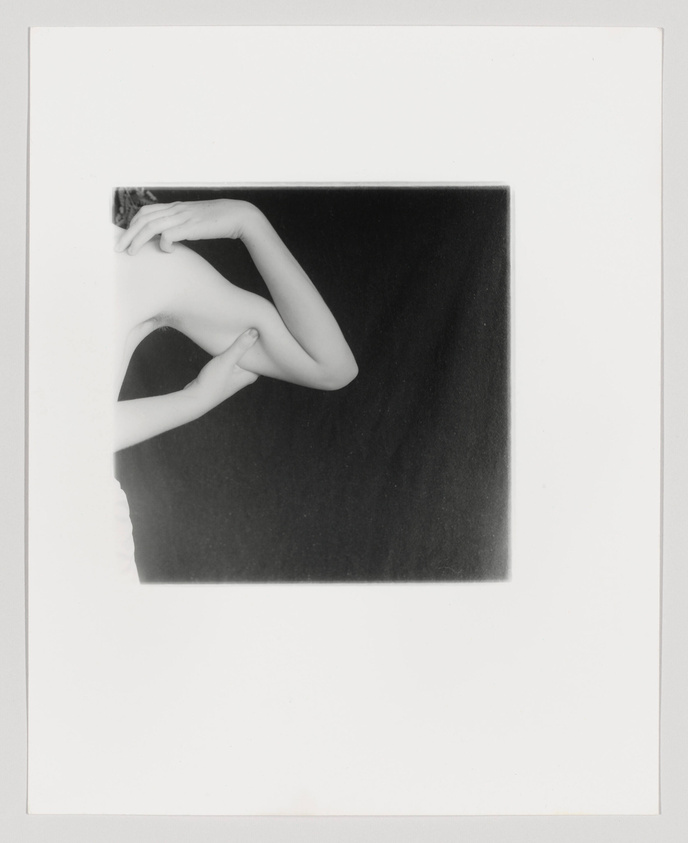 A black and white artistic photograph showing a person's arms and hands positioned in a square frame, creating a geometric composition with negative space.