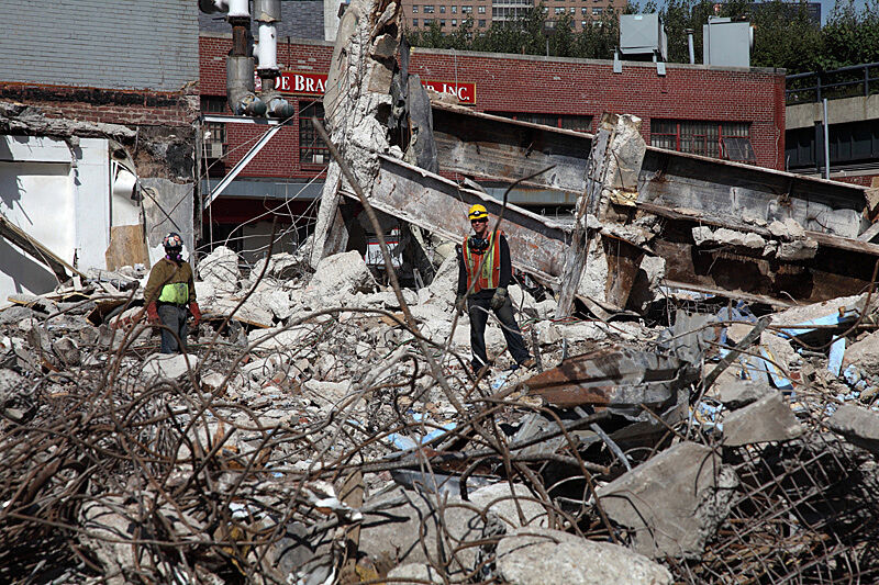 Rubble in foreground and worker behind.
