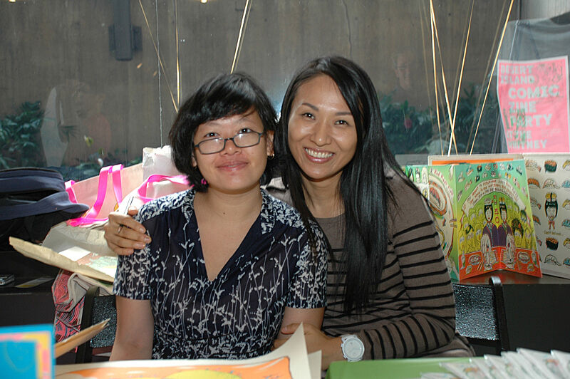 Artists smile for the camera in front of prints.