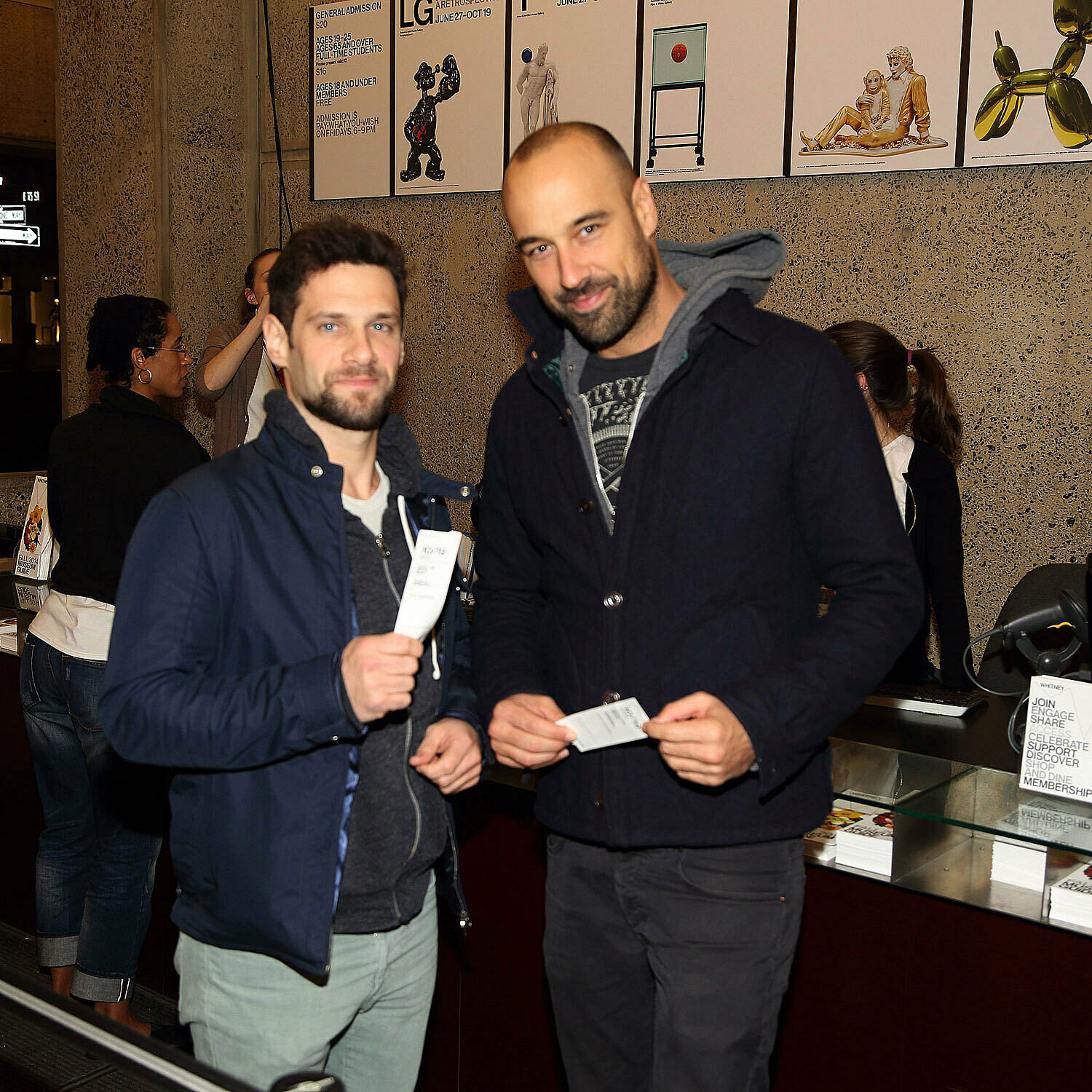 Two men holding up tickets.