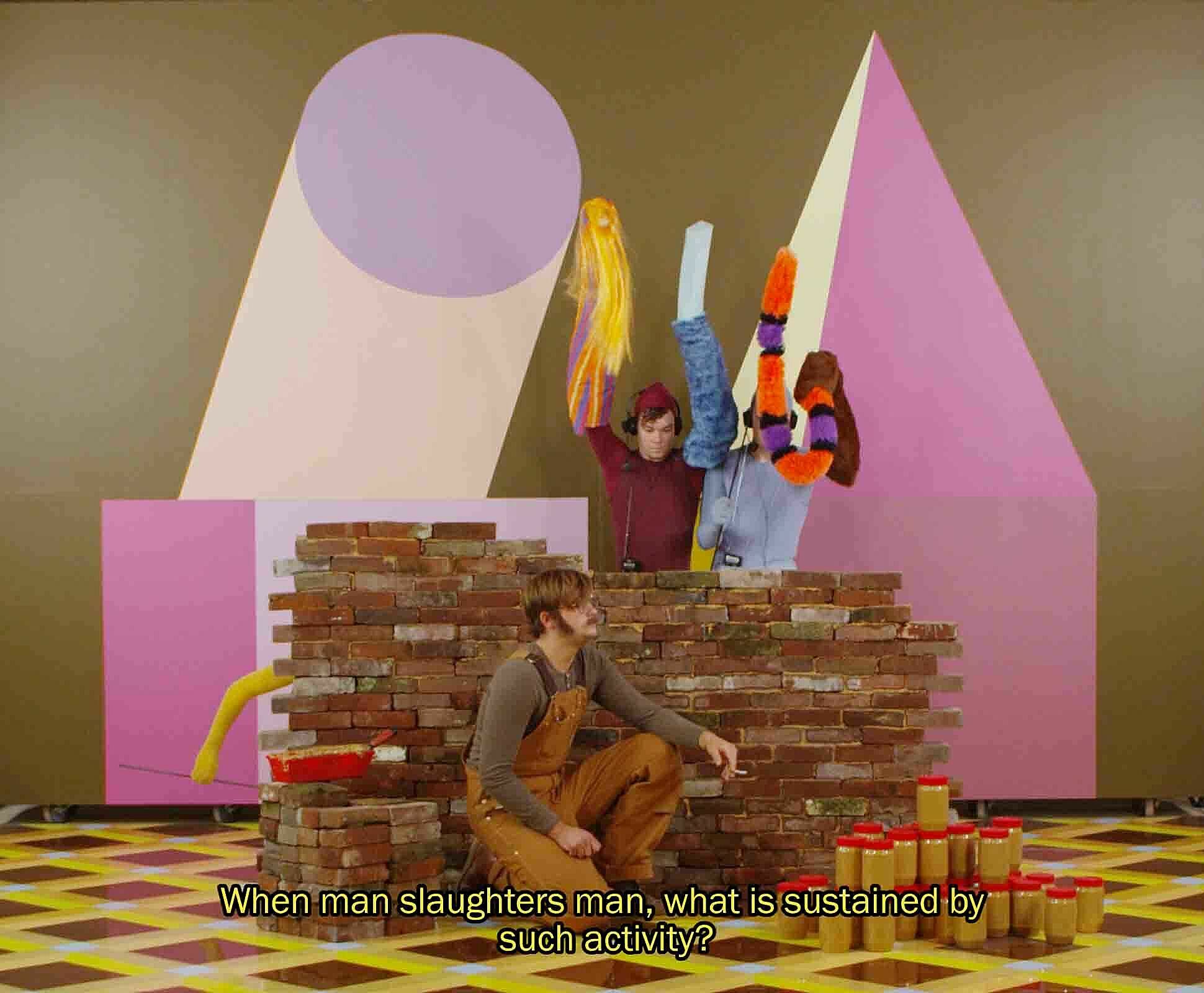 A still from a film work by Alex Da Corte. Three figures stage a puppet show in a fantasy landscape