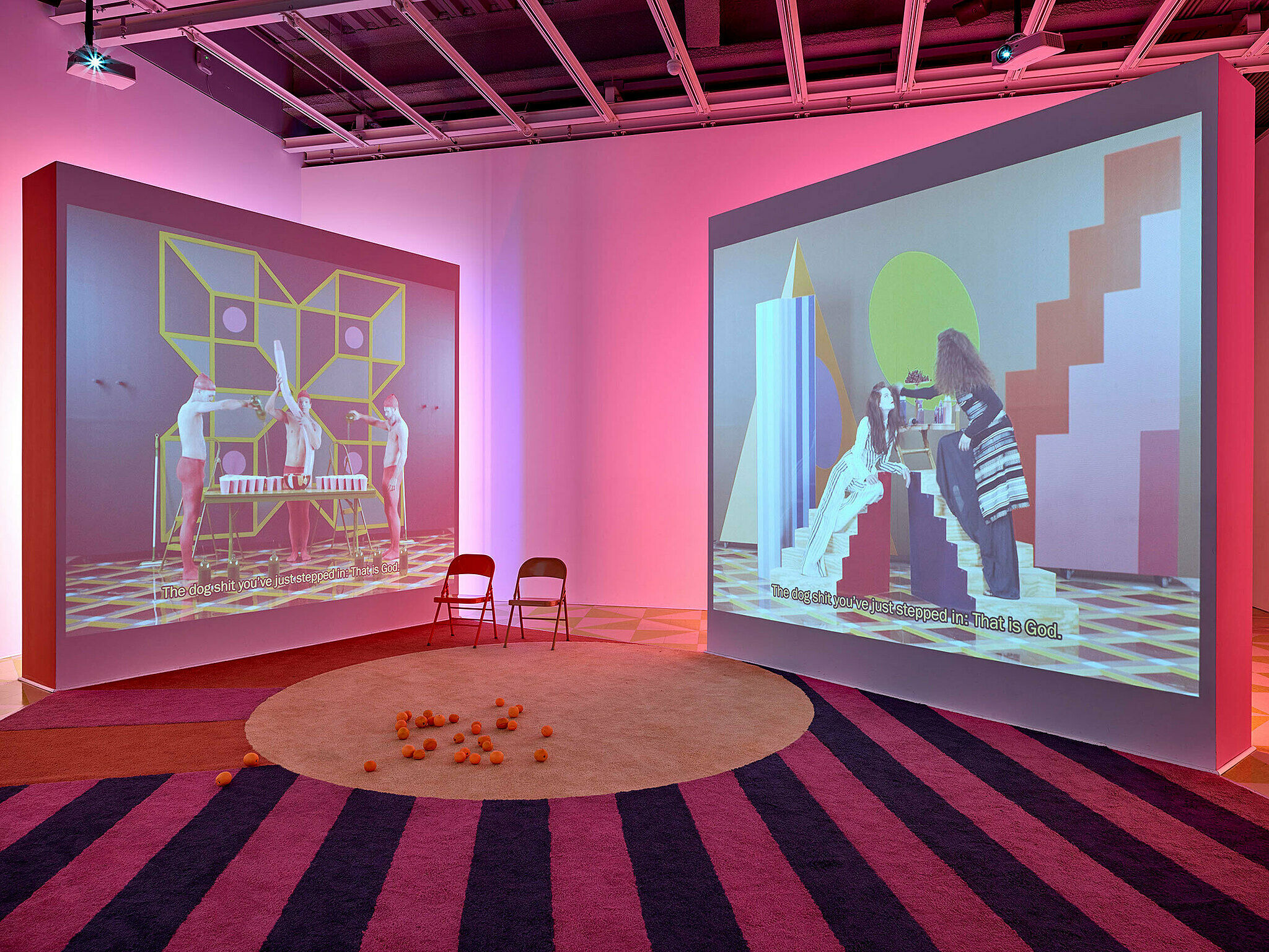Installation view of Easternsports; two videos projected on large screens in neon pink room 