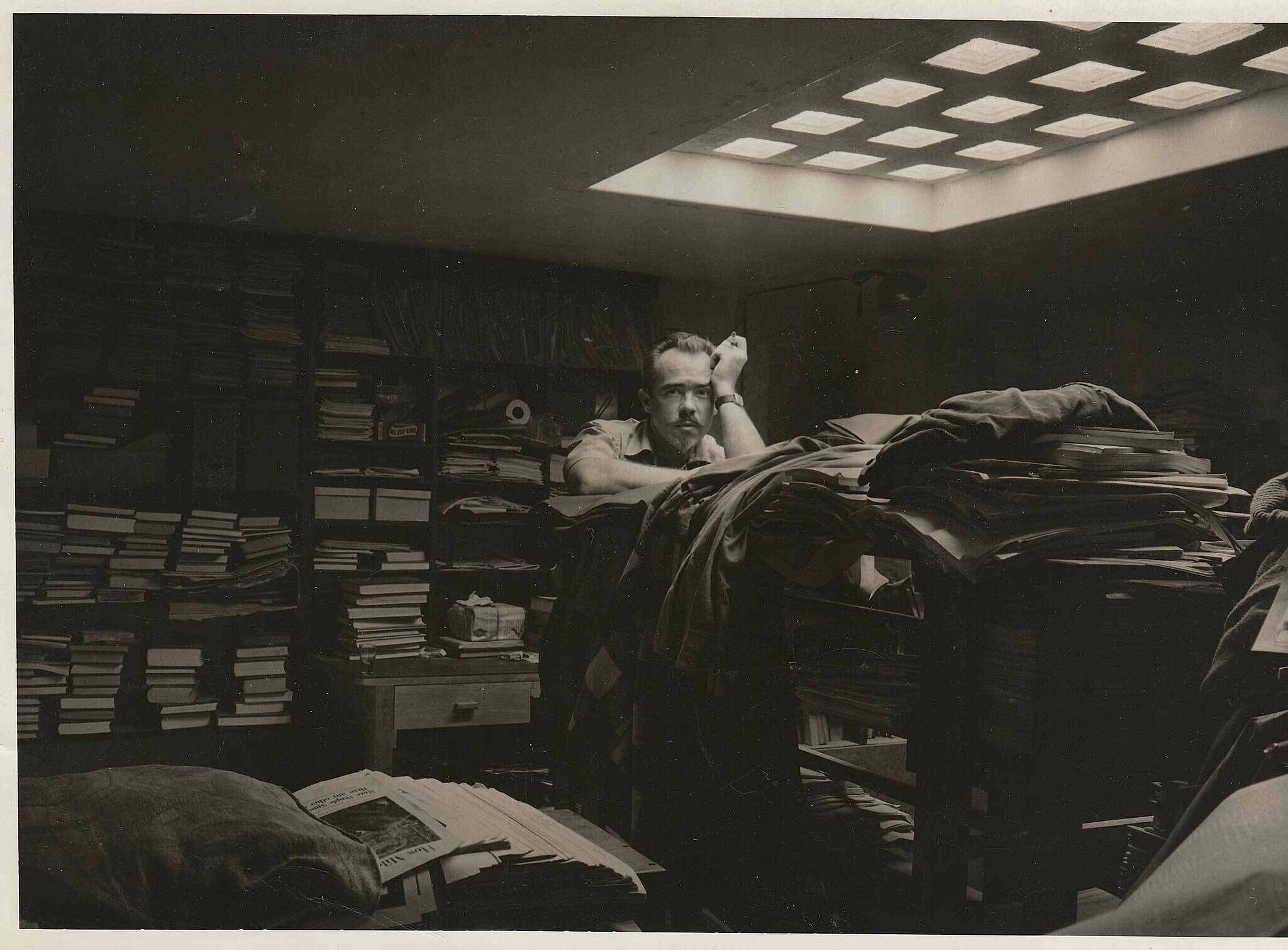 The composer Conlon Nancarrow stands amid papers and books in his library. 