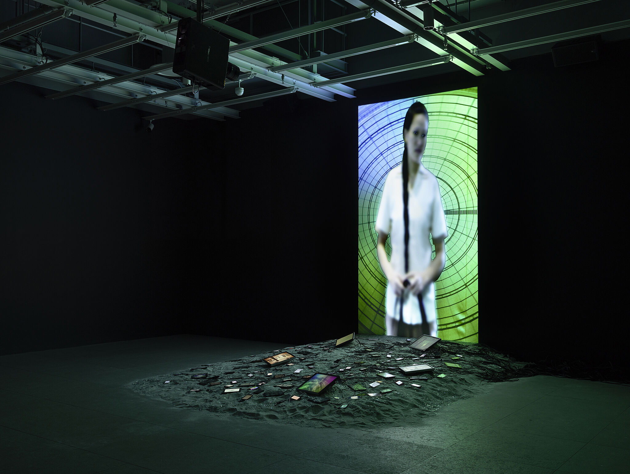 Video installation by Sophia Al-Maria with an image of a woman on a blue and green screen.