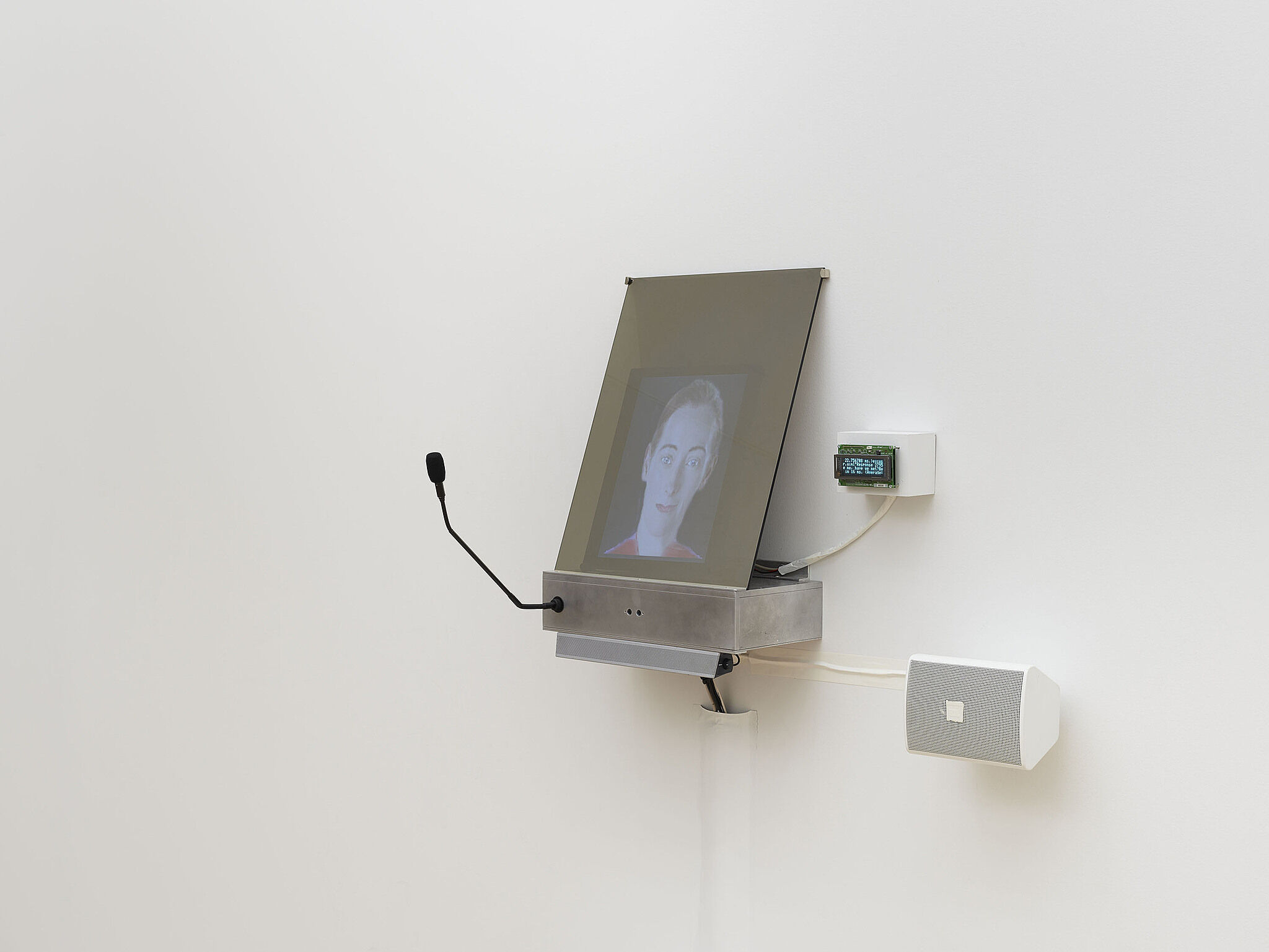 A small video screen on the wall projecting a person's face.