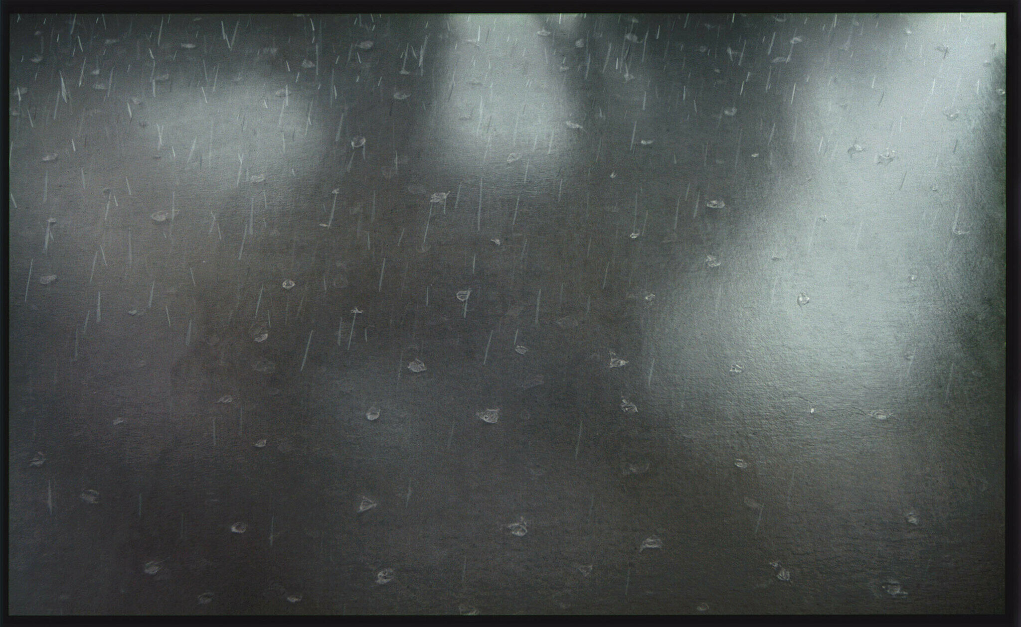 Raindrops appear to strike a concrete floor with blurred shapes in the reflection.