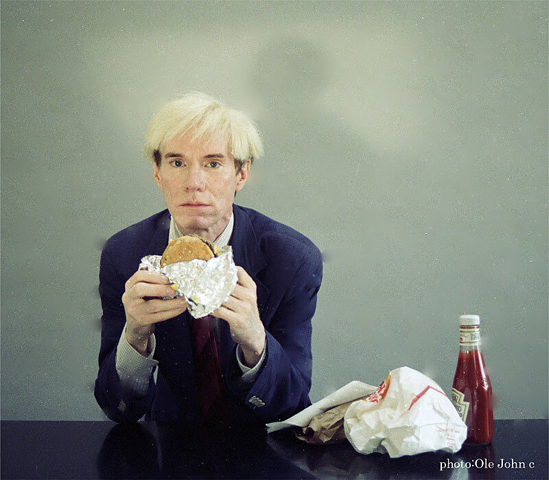 Andy Warhol eating a hamburger.