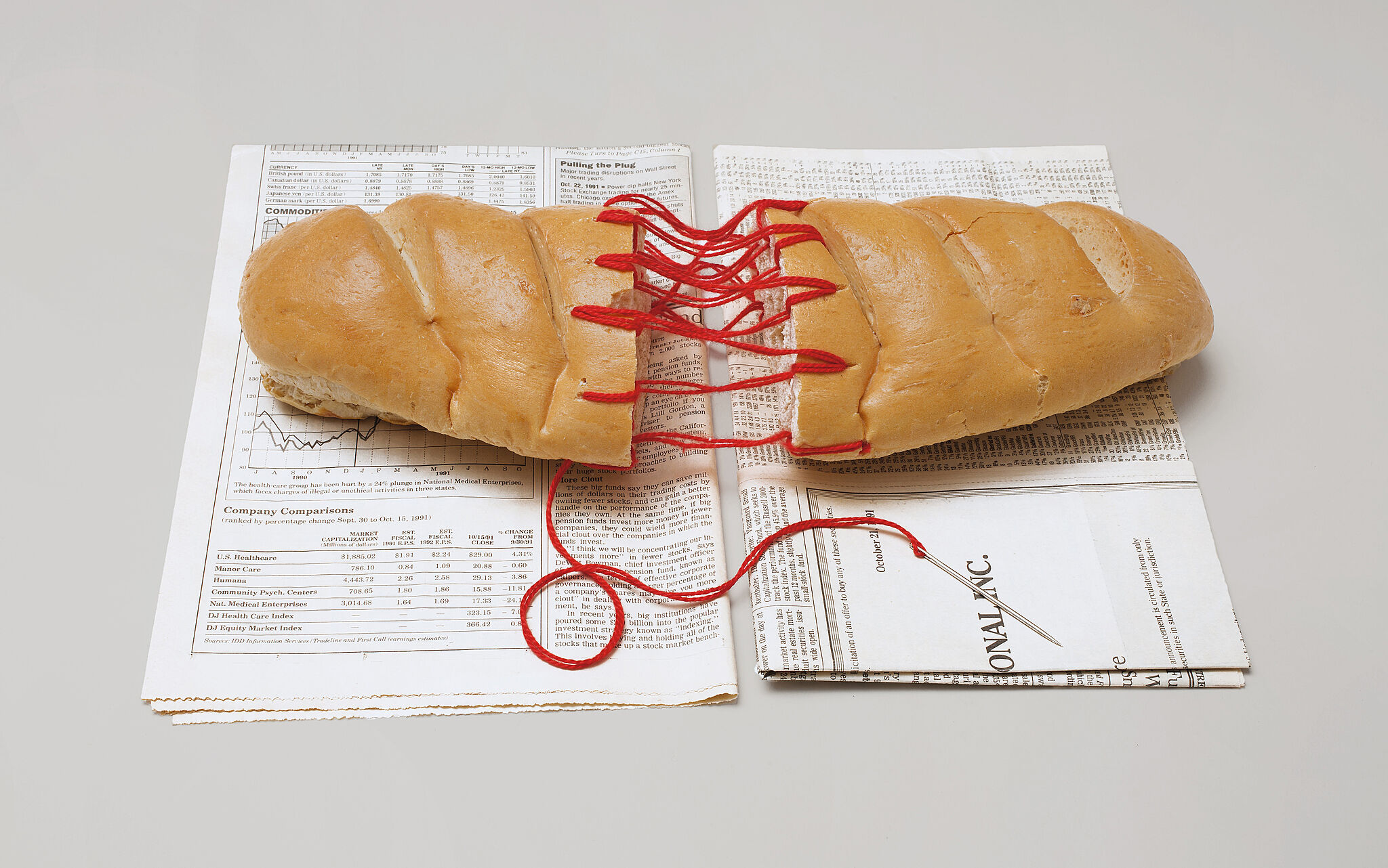 A color photograph of a loaf of bread bound with red thread. 