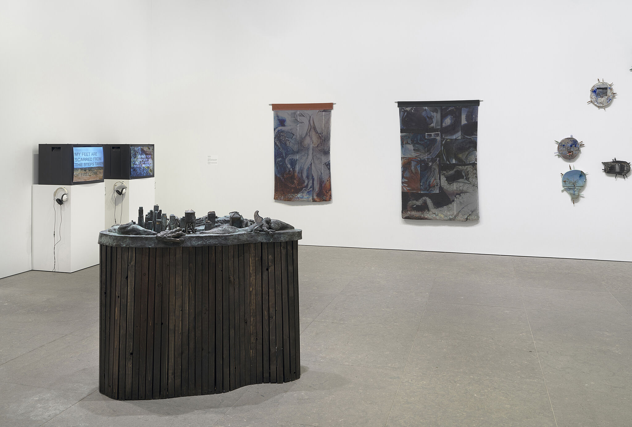 Two monitors, a sculpture, and a number of pieces on a wall.