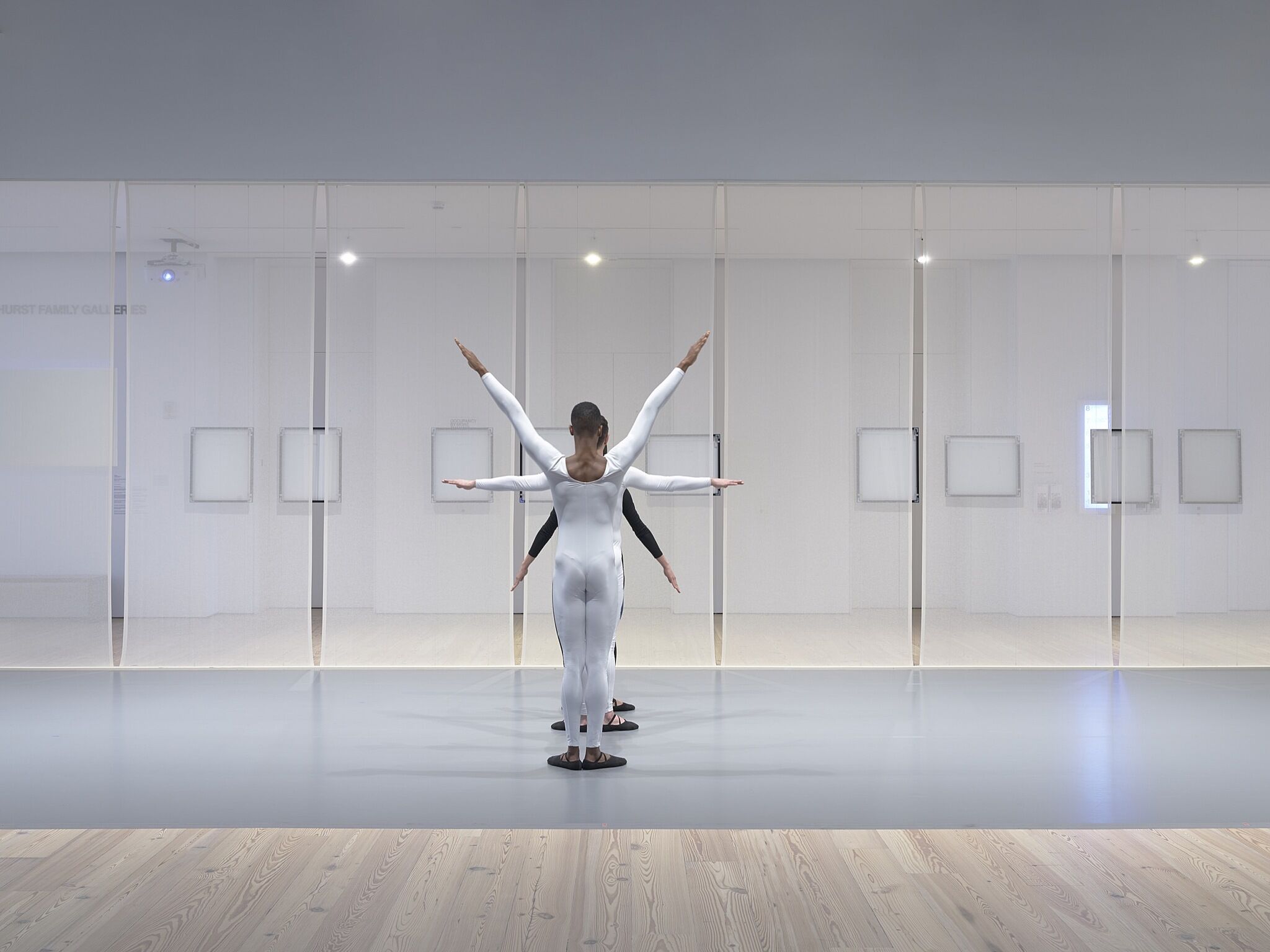 Three dancers perform in a gallery space.